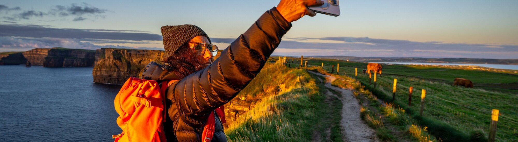 Une voyageuse prenant un selfie face aux Falaises de Moher - © Tolo 