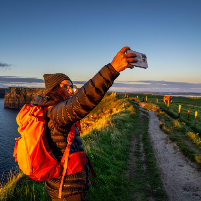 Une voyageuse prenant un selfie face aux Falaises de Moher - © Tolo
